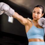 Mulher boxeadora posando com atitude, simbolizando empoderamento feminino nas artes marciais.