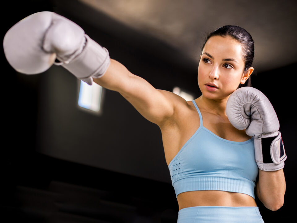 Mulher boxeadora posando com atitude, simbolizando empoderamento feminino nas artes marciais.